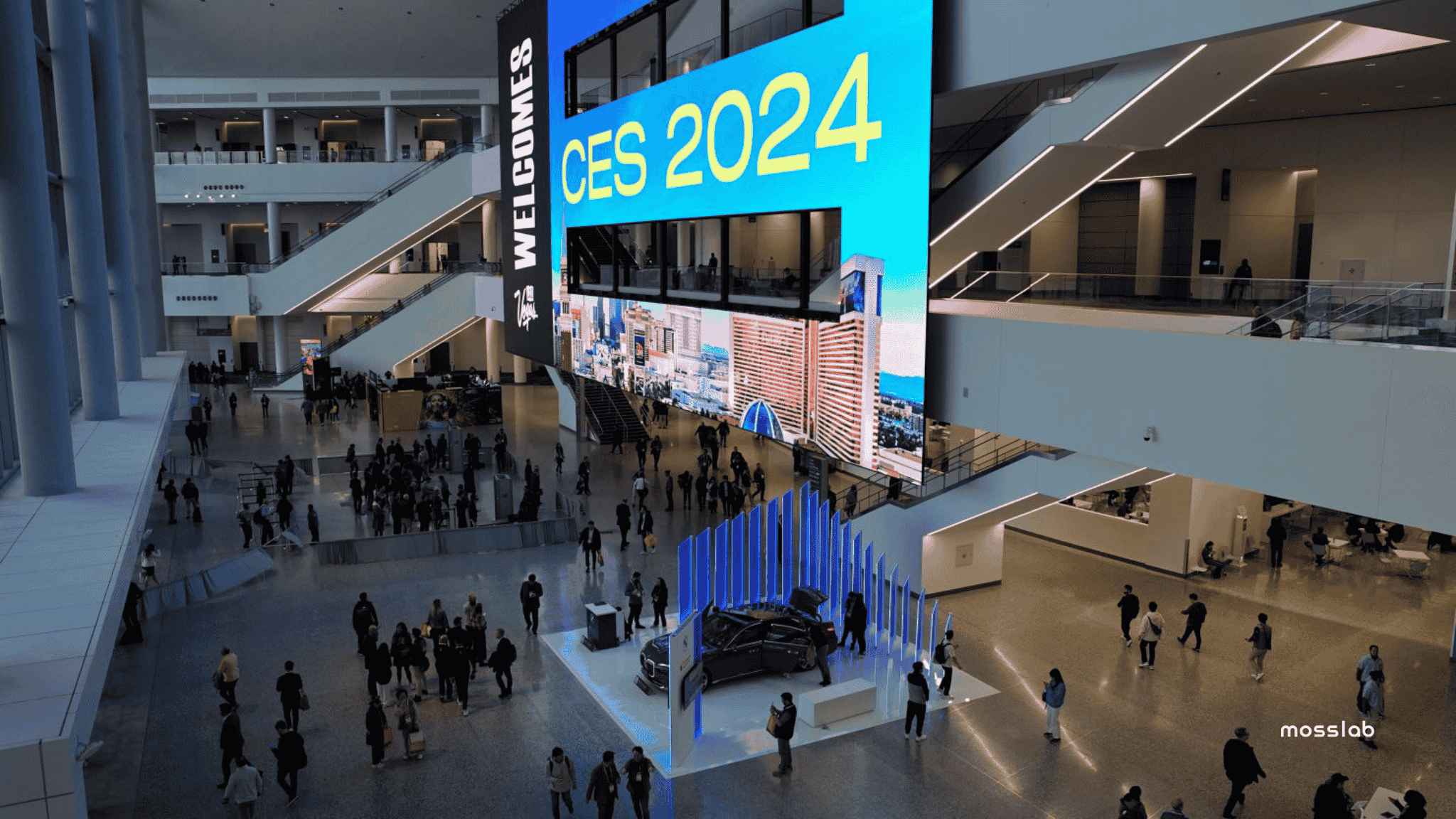 CES 2024 exhibition hall with attendees and a large digital display featuring “CES 2024” in bright blue and yellow.